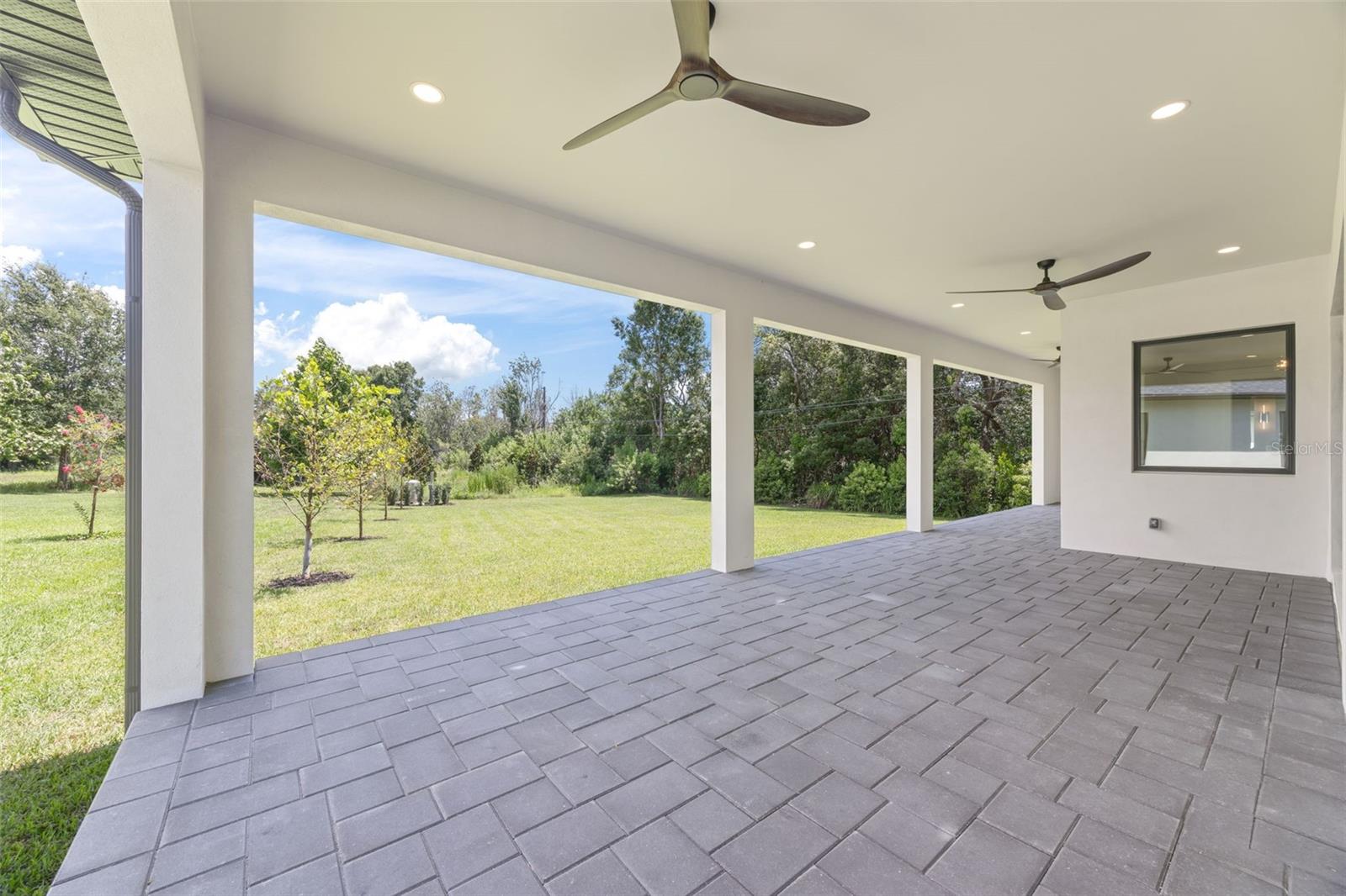 Covered paver lanai, pre-plumbed for a future outdoor kitchen, overlooking the beautifully landscaped yard with premium St. Augustine sod and mature native pine trees.