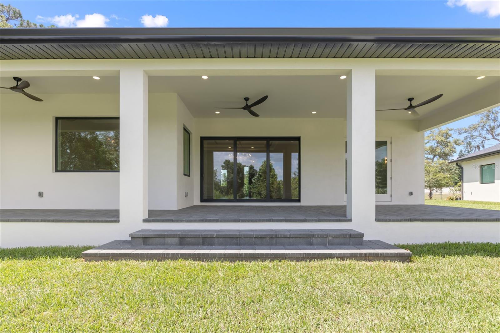 Covered paver lanai, pre-plumbed for a future outdoor kitchen, overlooking the beautifully landscaped yard with premium St. Augustine sod and mature native pine trees.