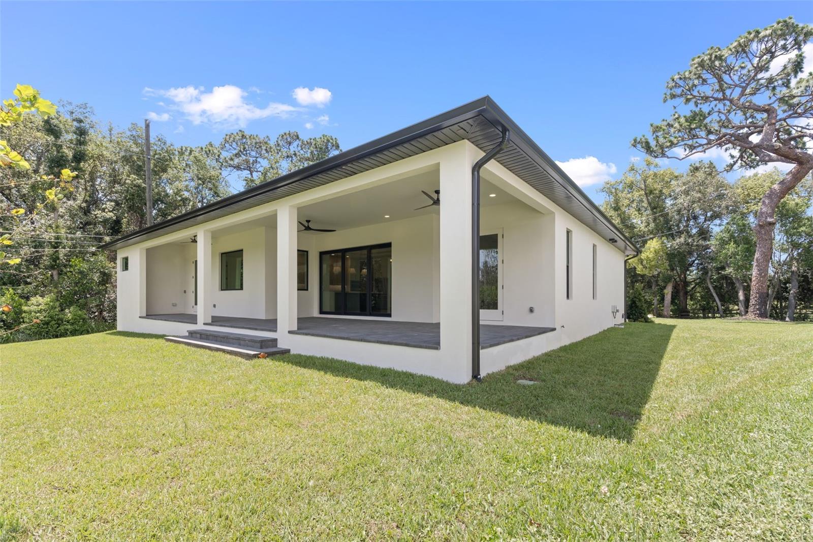 Covered paver lanai, pre-plumbed for a future outdoor kitchen, overlooking the beautifully landscaped yard with premium St. Augustine sod and mature native pine trees.