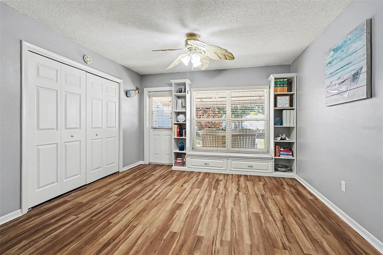 Florida room showing custom build in designer shelving with window seat and cabinets.