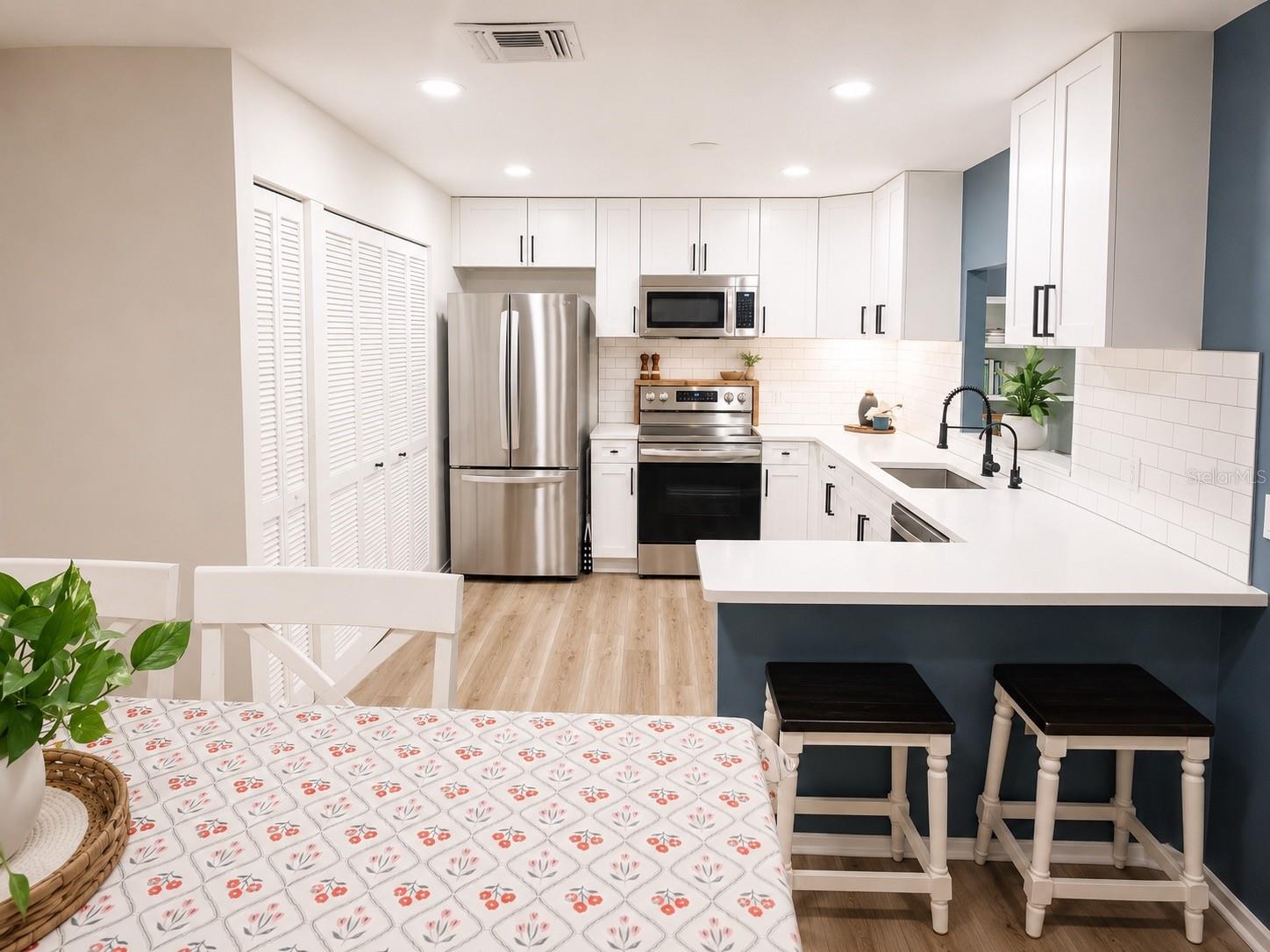 Kitchen with laundry closet featuring a full-size washer, dryer, and overhead storage cabinets.
