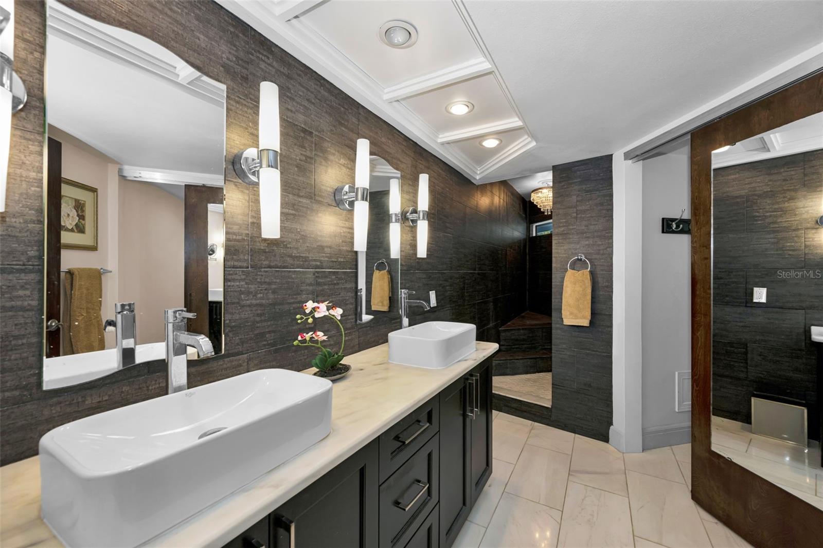 The master bath with double vanities, custom lighting and mirrors, huge walk in shower lit by a gorgeous chandelier! There is a linen closet and private toilet area as well.