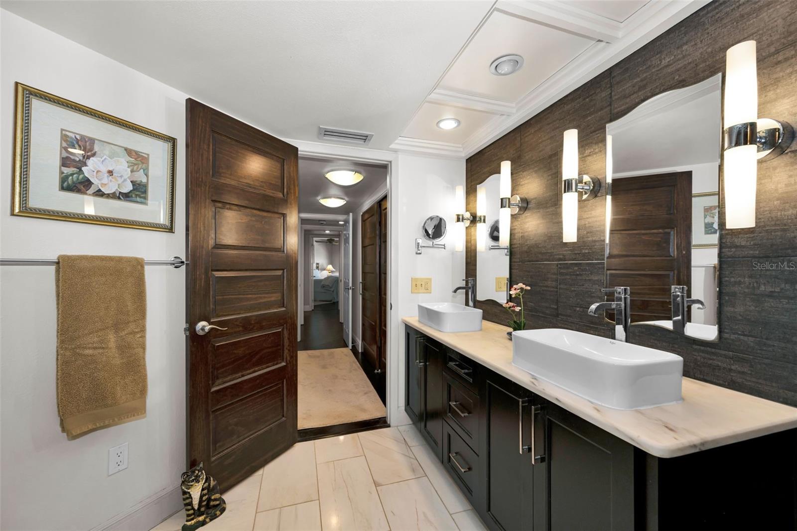 Master bath with distinct double sinks and lovely sconce lighting, custom mirrors and tile backsplash.