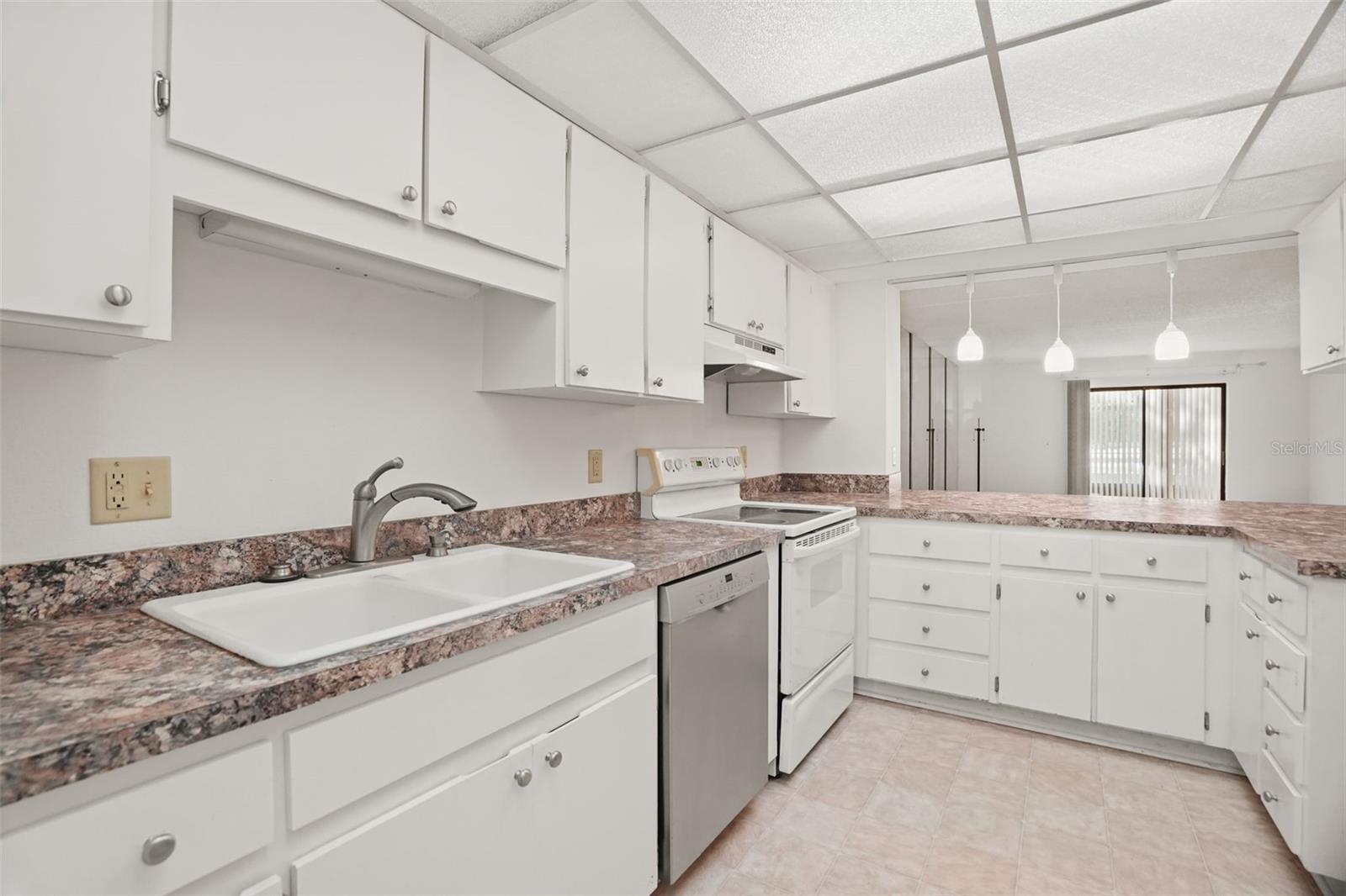 Generous cabinet storage, expansive counter space, and a pass-through accented by three pendant lights create a kitchen that's both functional and inviting.