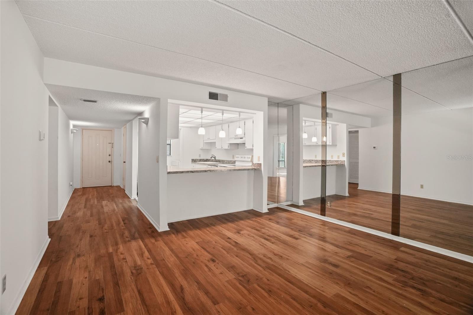 Open and Connected. A breakfast bar with three pendant lights defines the kitchen without closing it off, while the mirrored dining wall reflects natural light and enhances the sense of space.