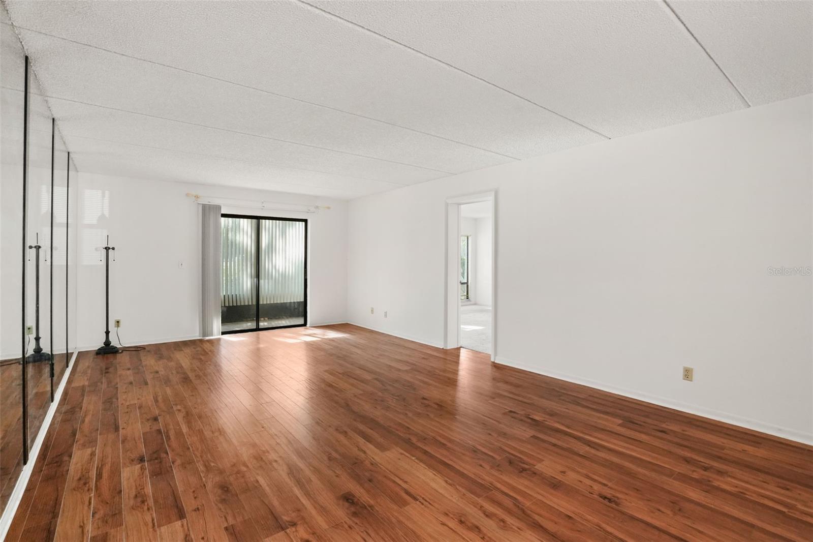 Spacious Living. Laminate flooring, expansive living and dining space, and a mirrored accent wall reflect natural light while enhancing the room's sense of openness.
