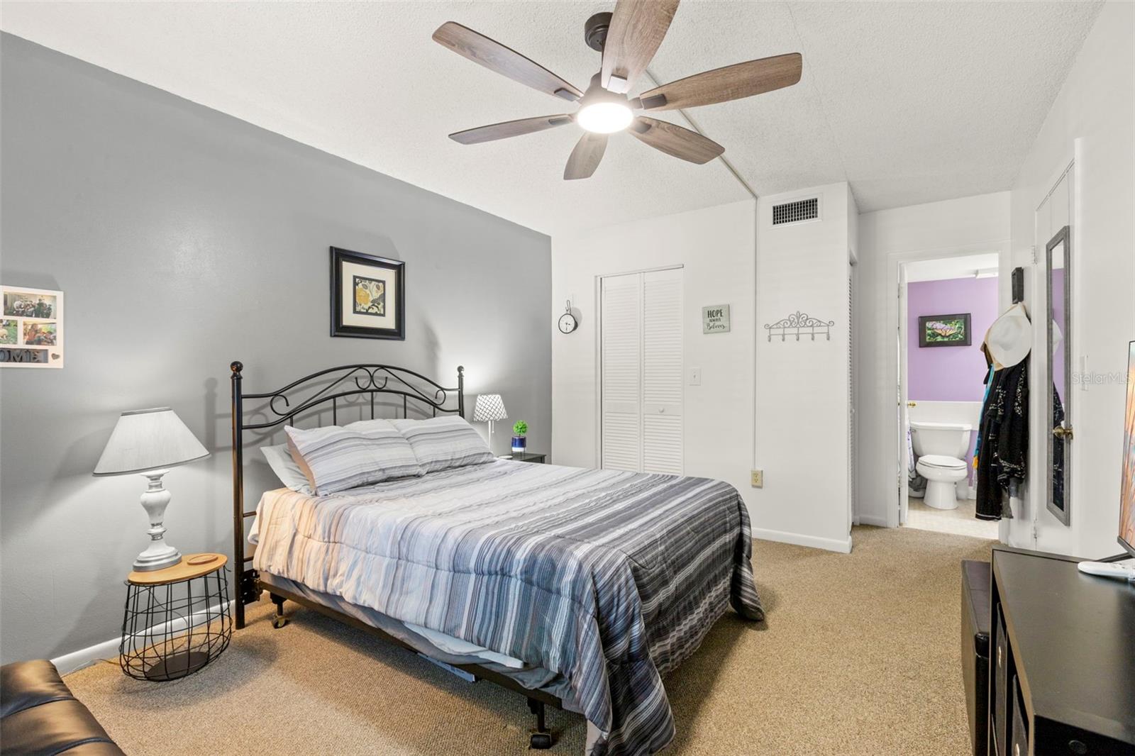 Soft gray accents and neutral carpeting create a calming bedroom with generous closet space and an adjoining bath.