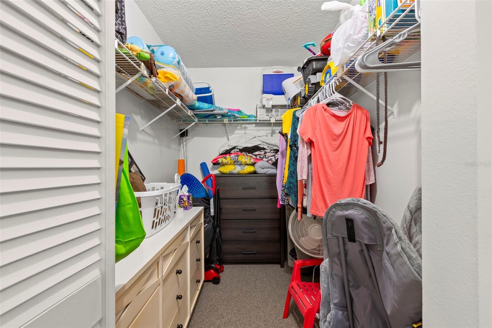 A spacious walk-in closet with built-in shelving provides generous storage and organization options.