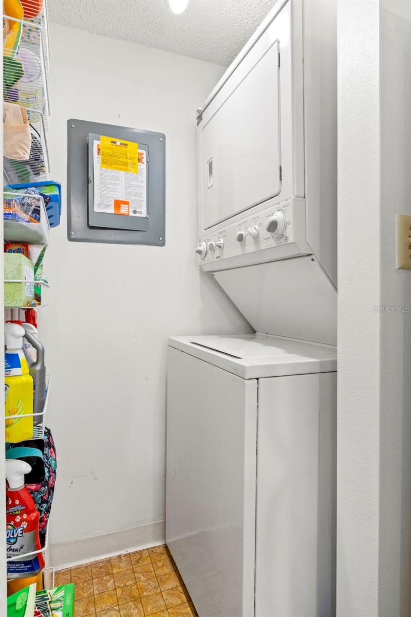 A dedicated laundry room houses a stacked washer and dryer while still leaving room for shelving and storage.