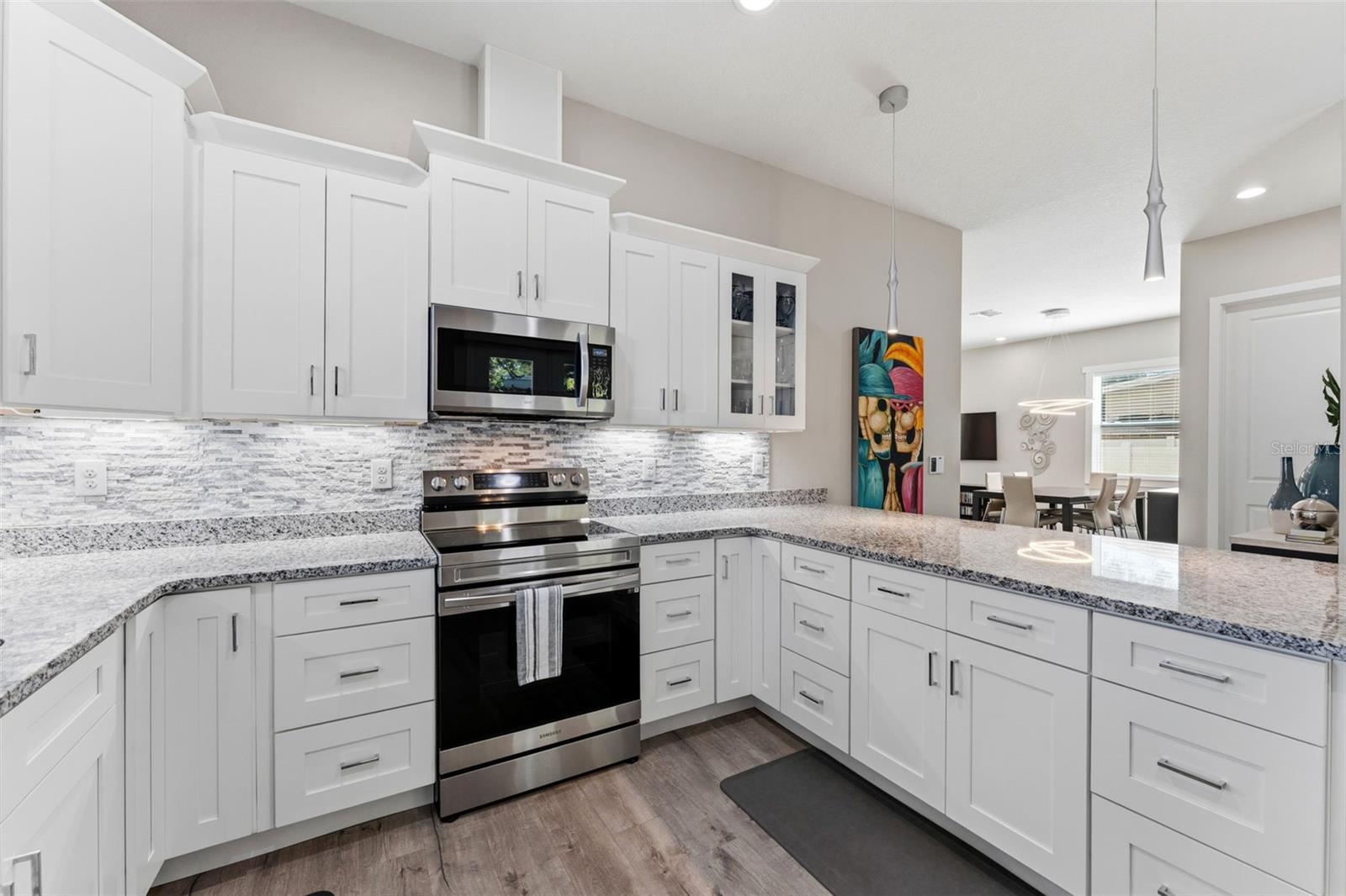 Open-concept kitchen with solid-wood cabinetry, granite countertops, stainless steel appliances, and custom lighting including under-counter kitchen lights.