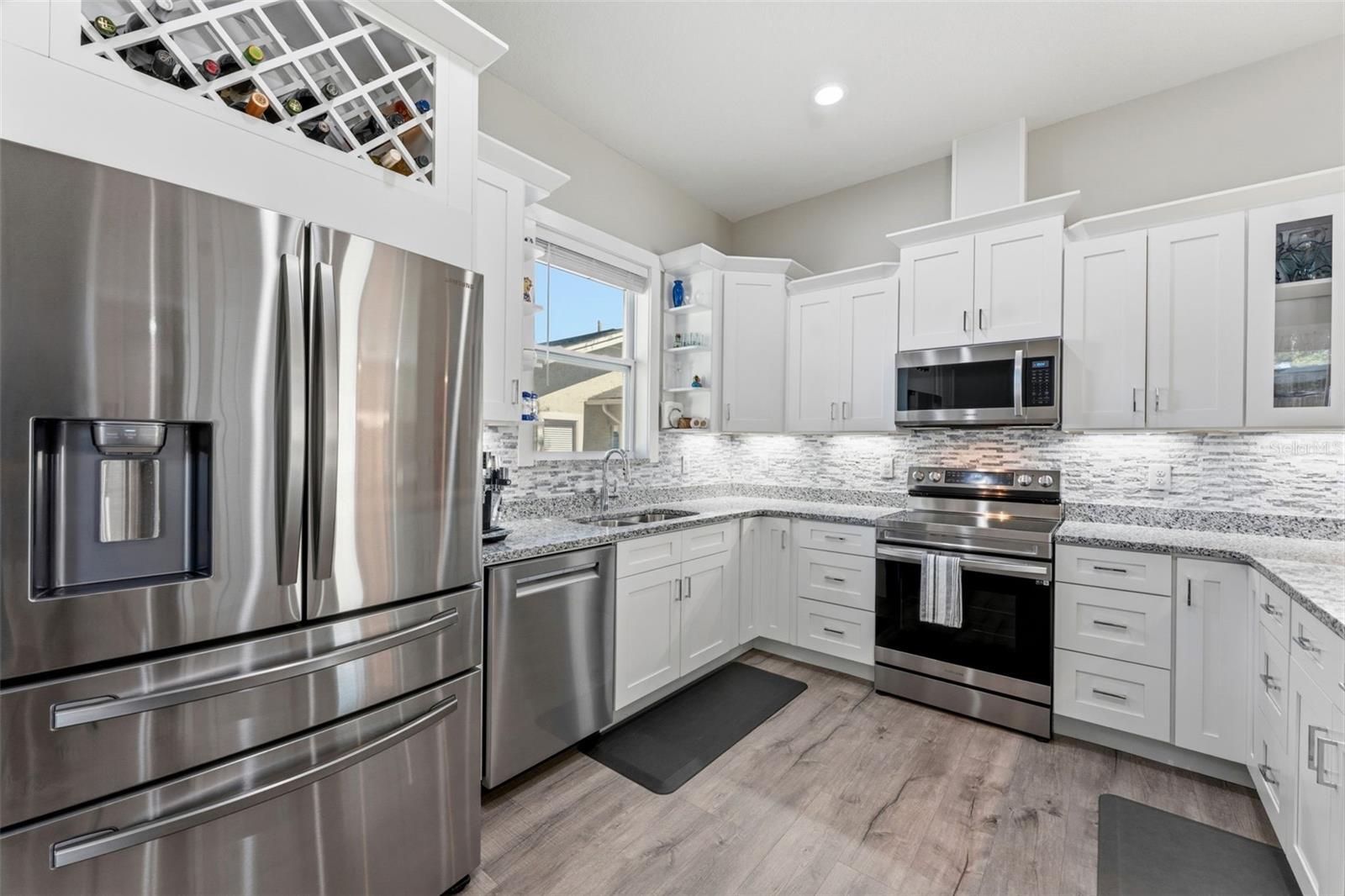 Open-concept kitchen with solid-wood cabinetry, granite countertops, stainless steel appliances, and custom lighting including under-counter kitchen lights.