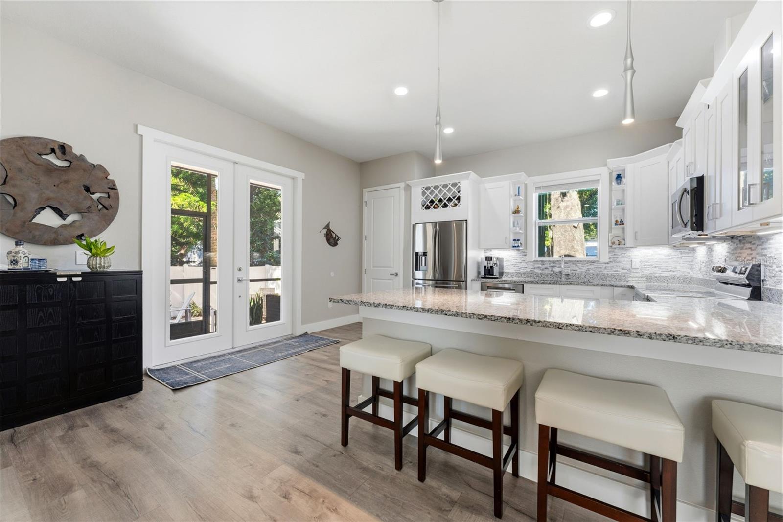 Open-concept kitchen with solid-wood cabinetry, granite countertops, stainless steel appliances, and custom lighting including under-counter kitchen lights.