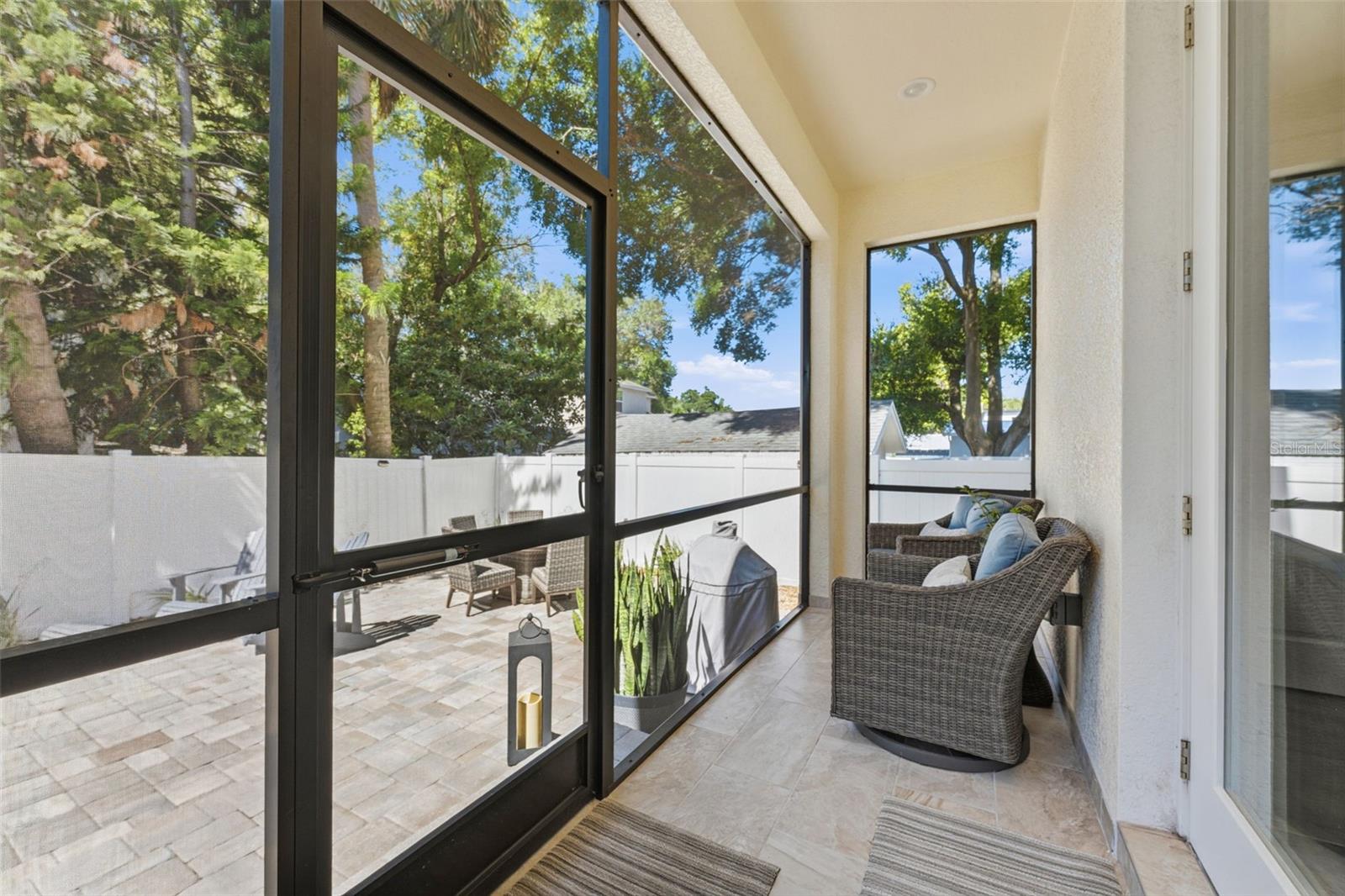 Screened-in porch overlooking a fully fenced in backyard with paver patio for entertaining, professional landscaping, and irrigation system