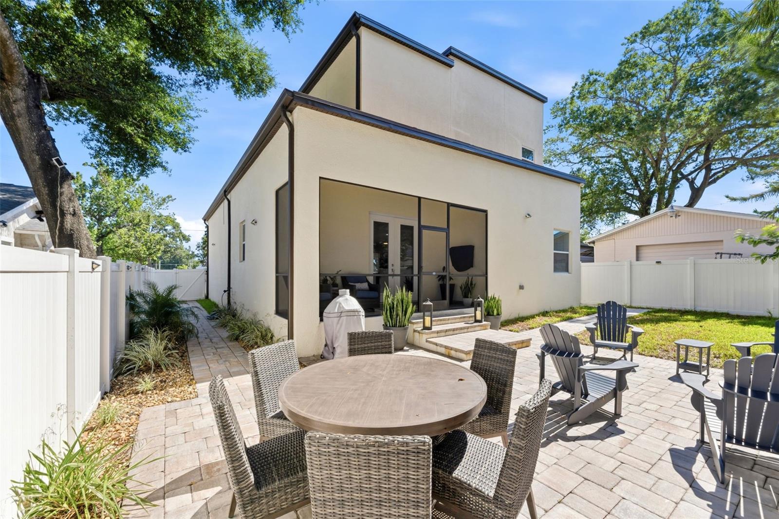 Fully fenced in backyard with a screened-in porch, paver patio for entertaining, professional landscaping, and irrigation system