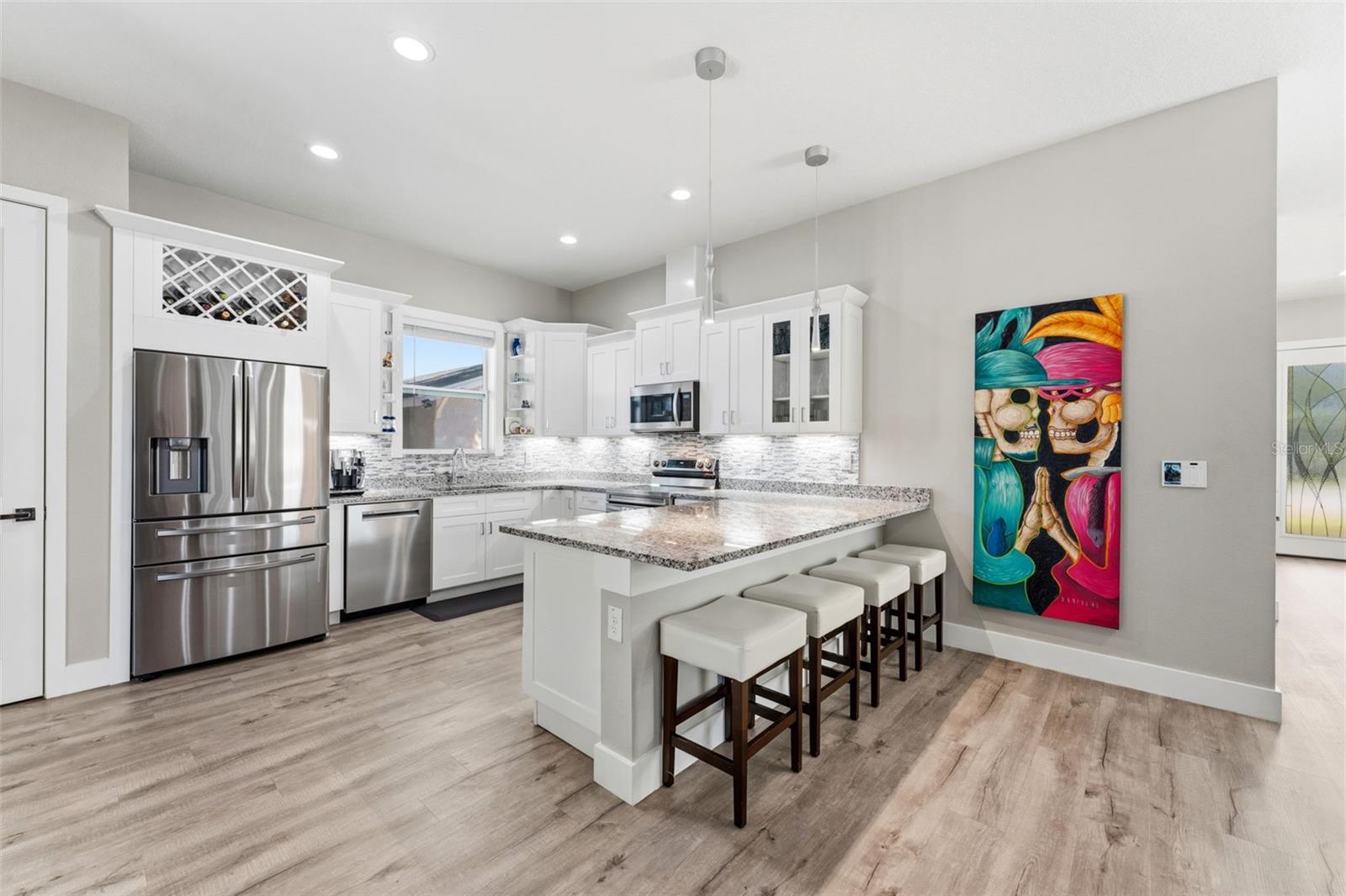 Open-concept kitchen with solid-wood cabinetry, granite countertops, stainless steel appliances, and custom lighting including under-counter kitchen lights.