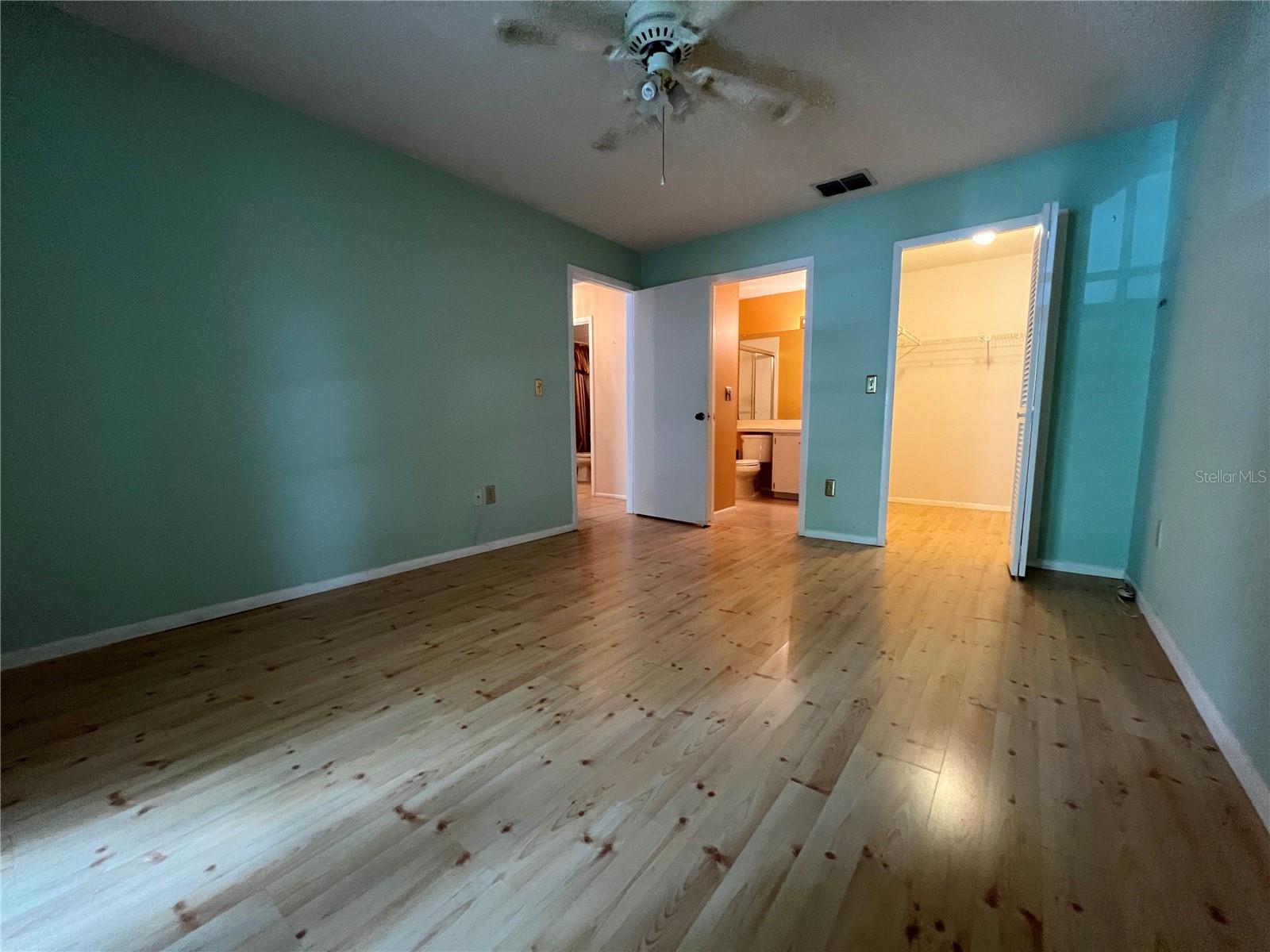 View of primary bedroom from french doors of patio toward closet and en suite bathroom.