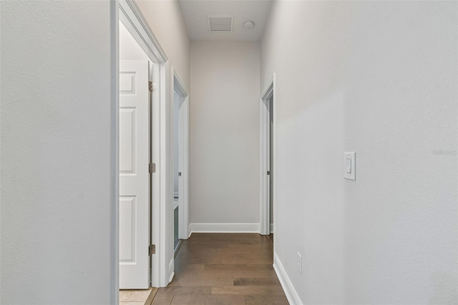 Hallway to guest full bath and two guest rooms