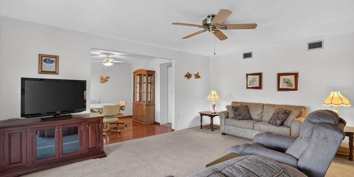 Spacious livcing room, dining room in background.  Foyer to righr.
