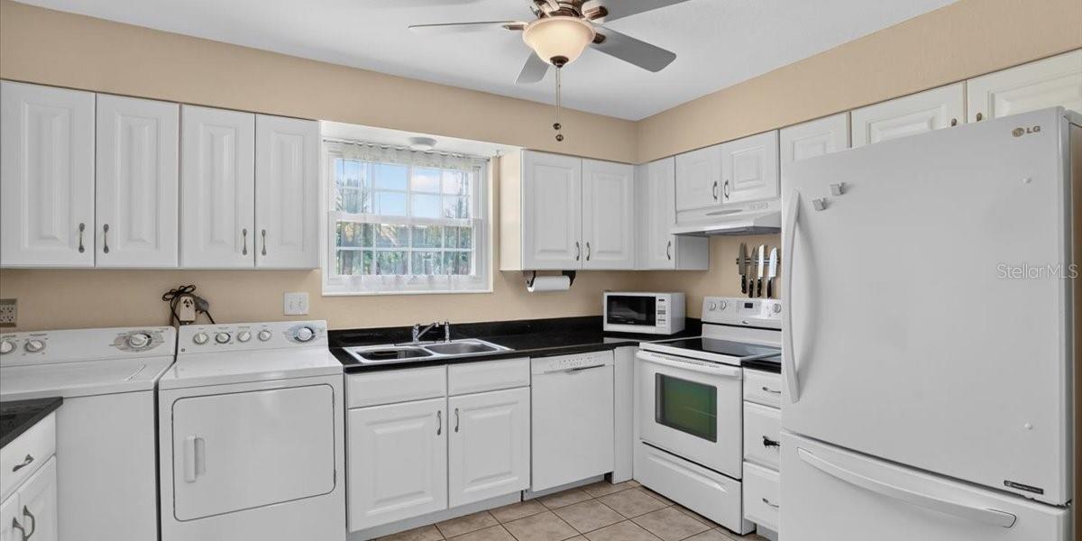 Light and bright kitchen wih newer appliances and attractive dark stone ountertops.