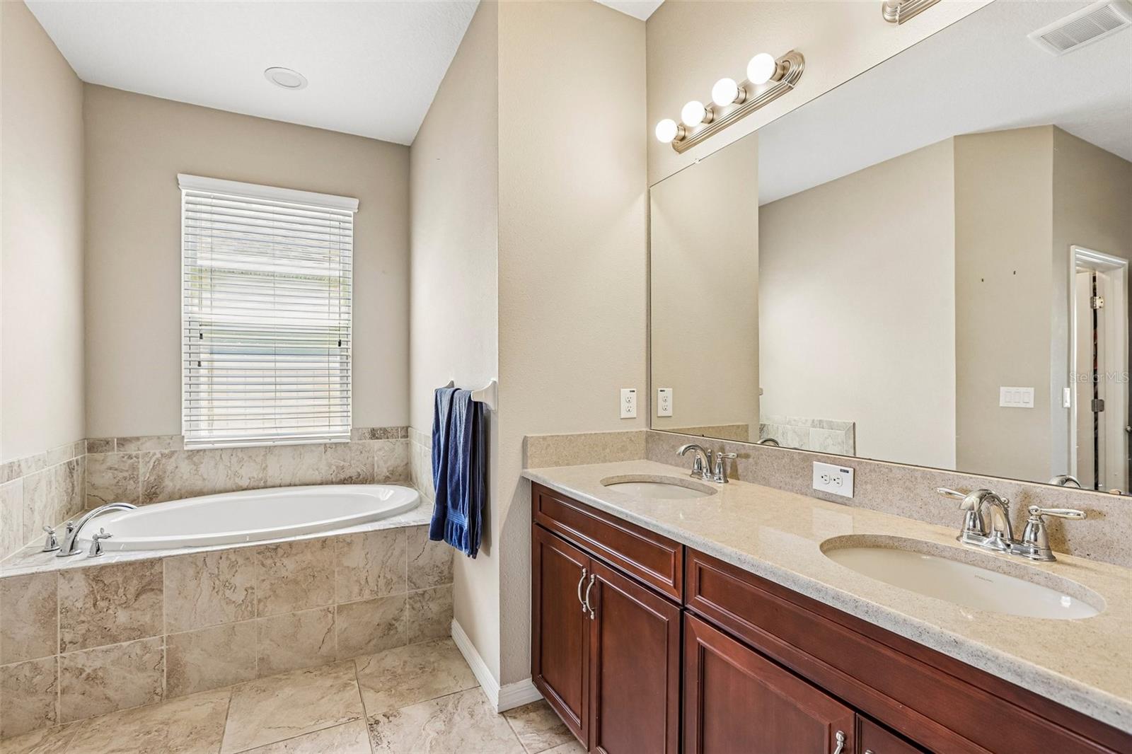 Primary Bathroom with dual vanity, soaking tub, walk in shower and 2 walk in closets