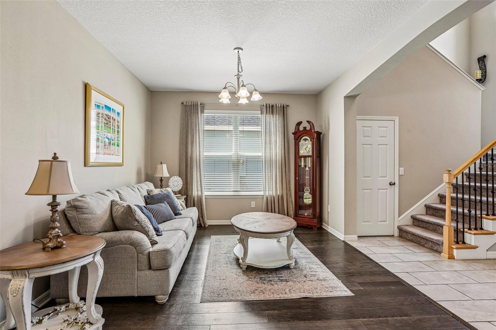 Inviting Living Room with hard wood floors and neutral colors.  View to the front door and stairs to 2nd floor