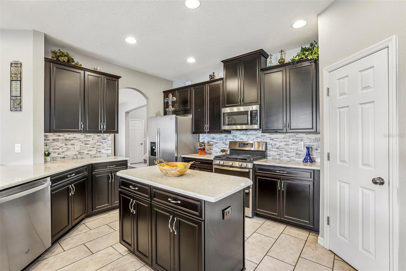 Kitchen area with 42" cabinets, stained appliances, gas range, beautiful backsplash, Island and quartz
