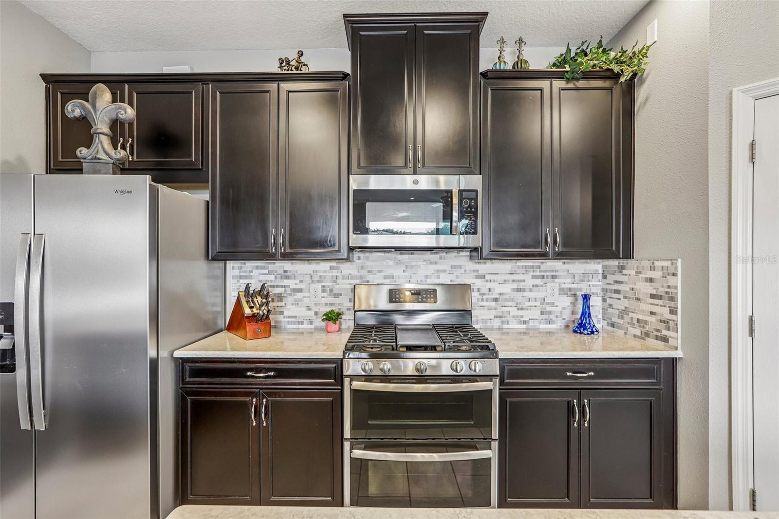 Kitchen area with 42" cabinets, stained appliances, gas range, beautiful backsplash, Island and quartz