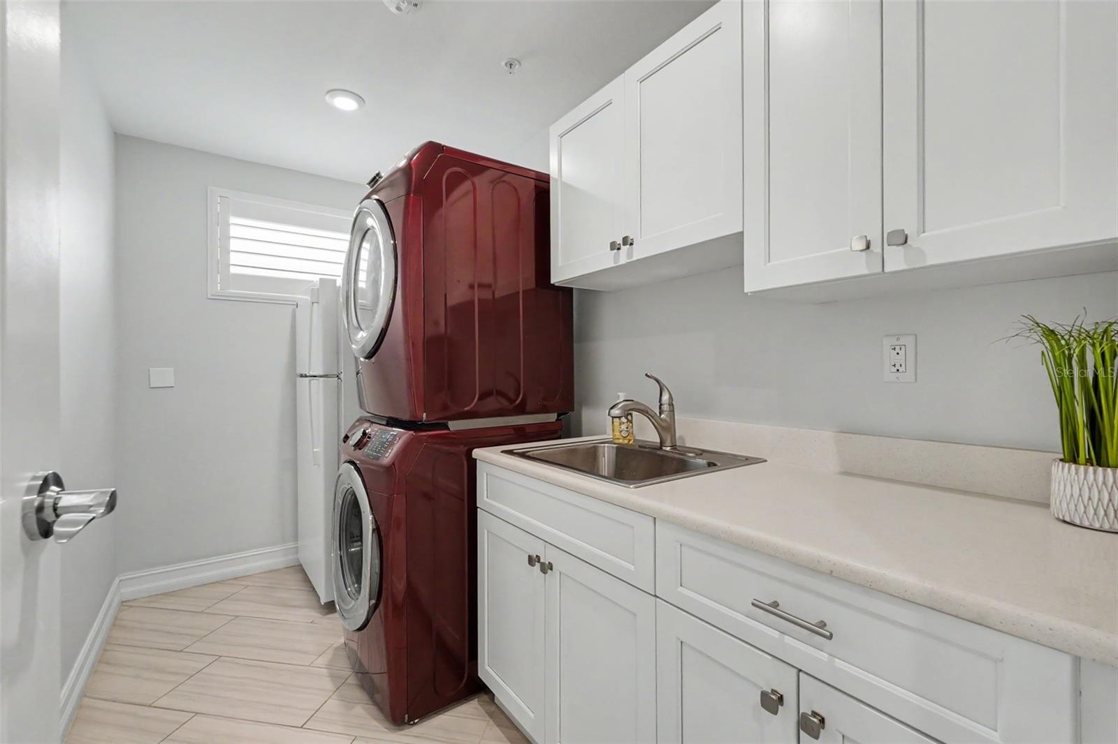 Inside laundry room with a sink and an extra refrigerator.