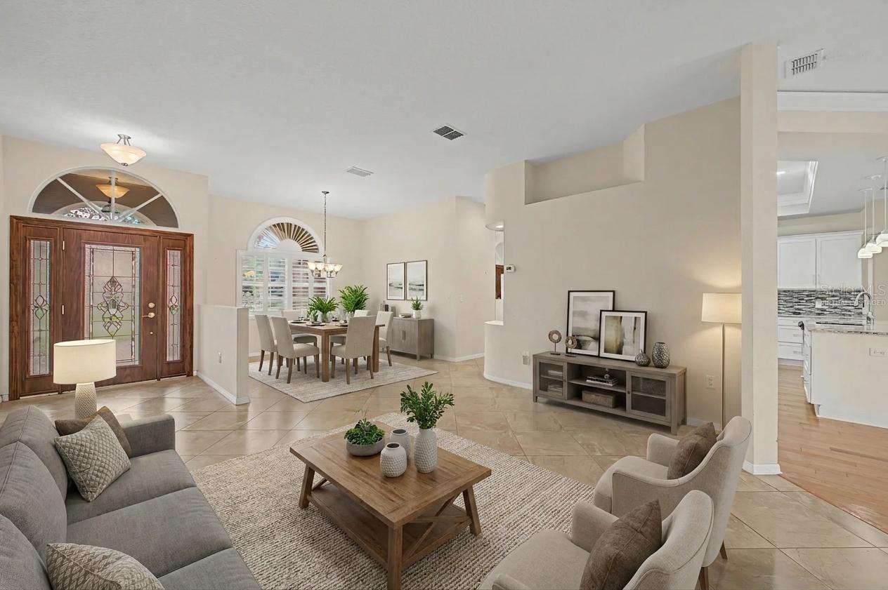 Stunning entryway featuring a beautiful wood front door that opens into a bright, open layout with neutral tones and large tile flooring throughout. Virtually staged formal dining room flows seamlessly into a well-designed sitting area, also virtually staged, showcasing the home’s versatile and inviting layout. The space highlights excellent natural light, tasteful finishes, and a welcoming, functional floor plan.