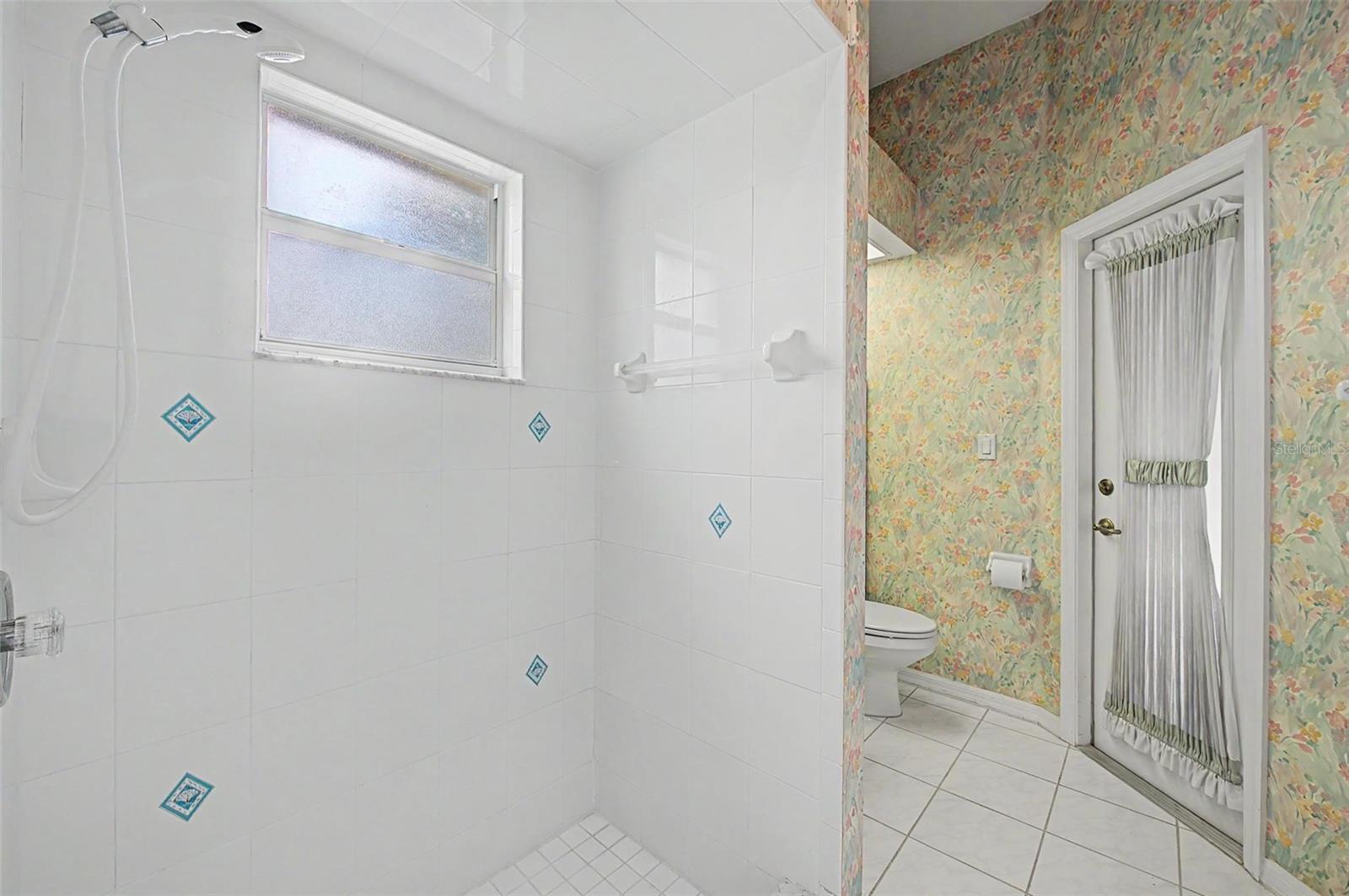 secondary full bathroom showcasing the spacious walk-in shower and convenient layout. A private exterior door provides direct access to the pool area, allowing this bathroom to function perfectly as a pool bath while also serving the secondary master bedroom.