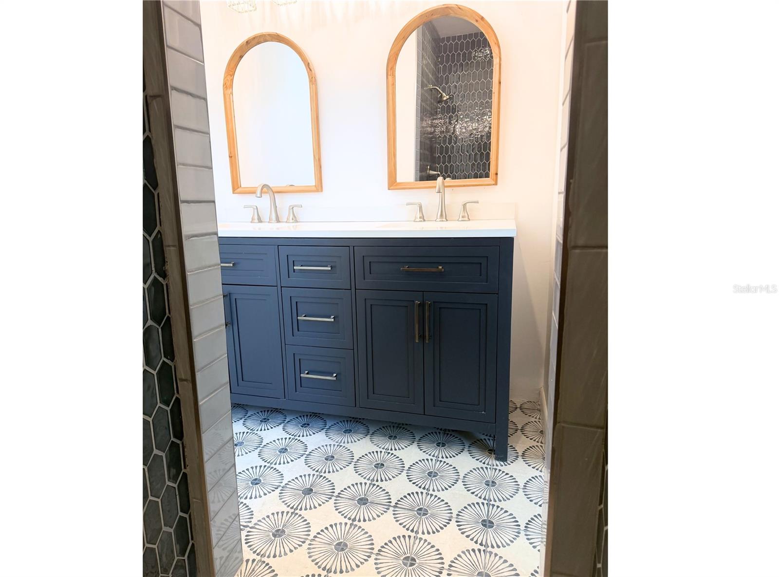 Primary Bathroom – Large double-sink vanity with a clean white countertop, beautiful patterned floor tiles, and crisp white walls that contrast perfectly with the sleek navy cabinetry.