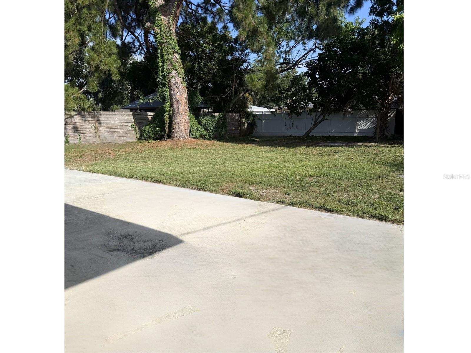 Expansive backyard with a spacious patio perfect for outdoor living; ideal for adding seating, a grill, and more.