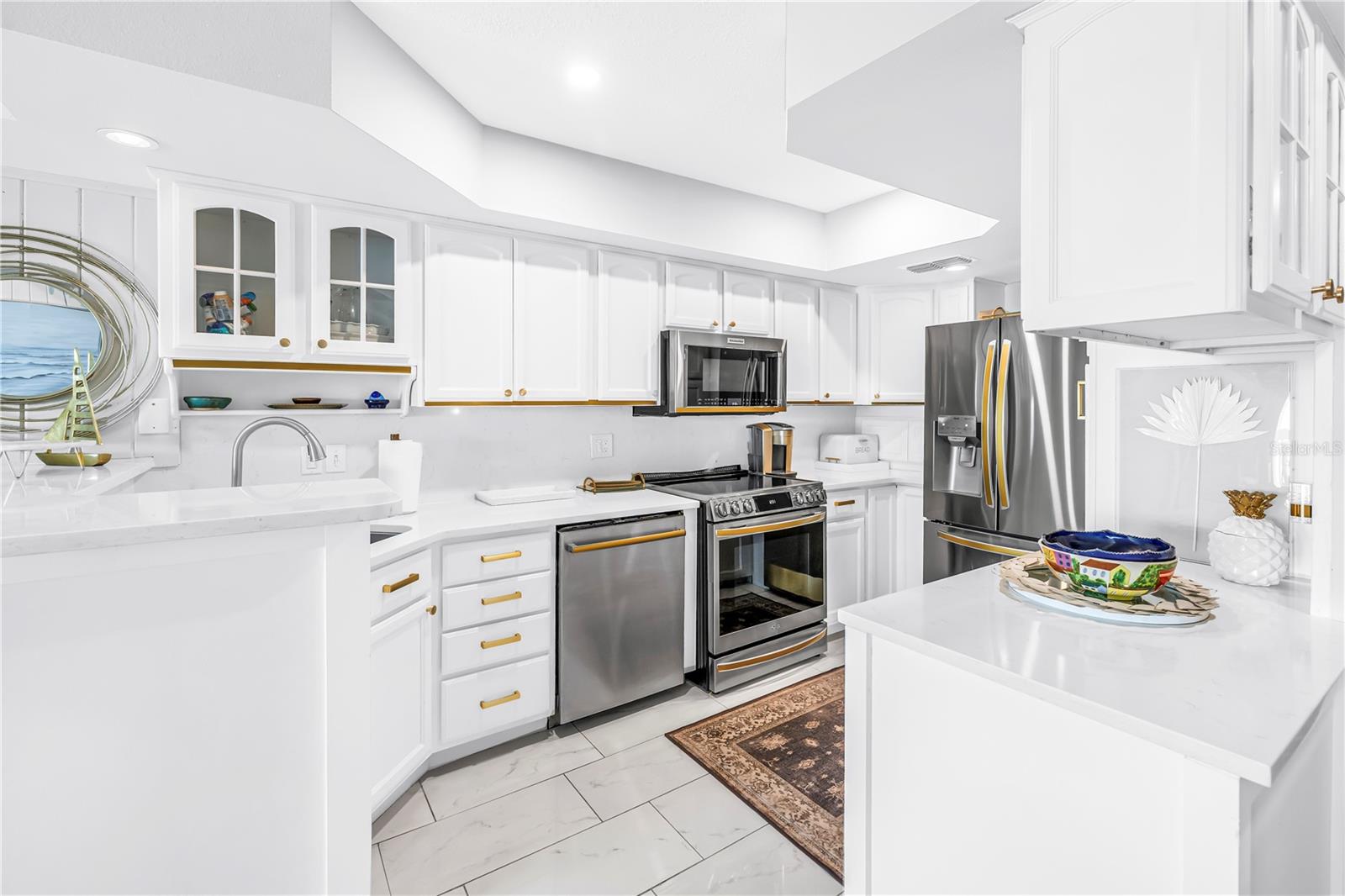 Light and bright kitchen with stainless steel appliances w/ gold accents throughout