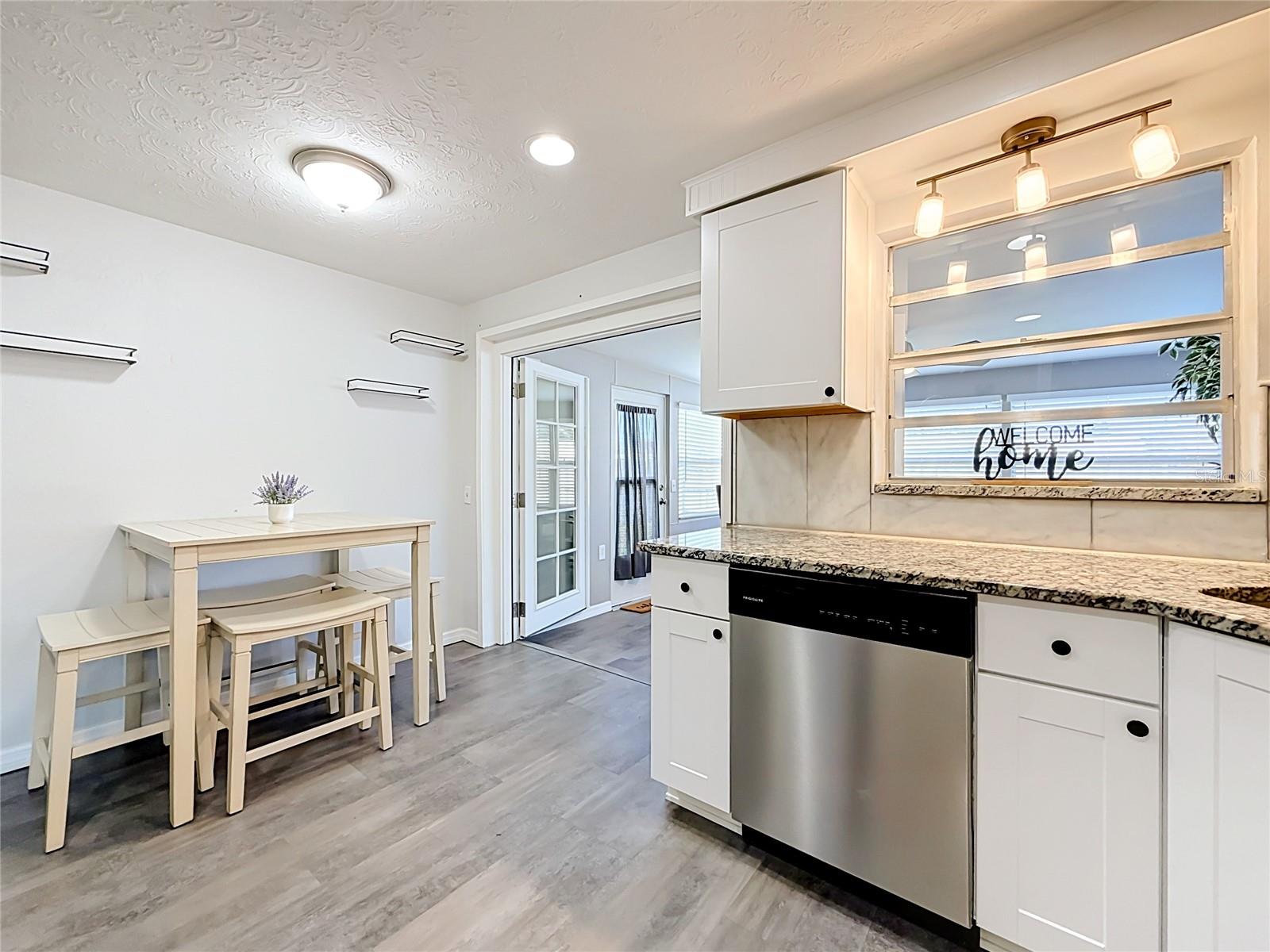 Stylish kitchen with granite countertops, tile backsplash, new luxury laminate flooring, stainless steel appliances, built-in oven, and ample storage