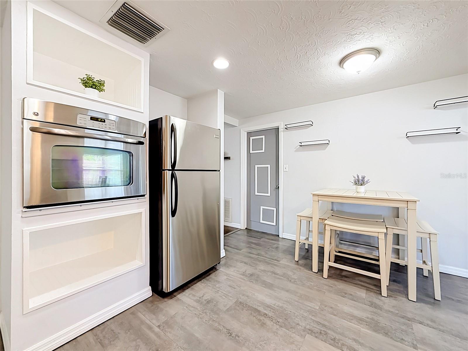 Stylish kitchen with granite countertops, tile backsplash, new luxury laminate flooring, stainless steel appliances, built-in oven, and ample storage