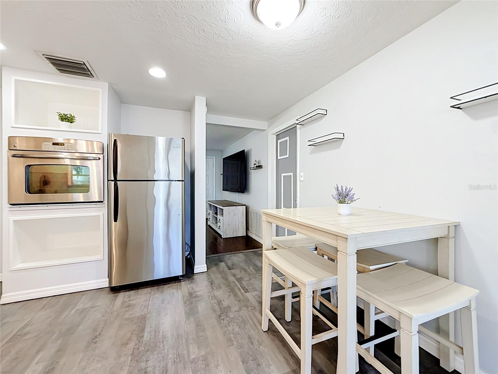 Stylish kitchen with granite countertops, tile backsplash, new luxury laminate flooring, stainless steel appliances, built-in oven, and ample storage