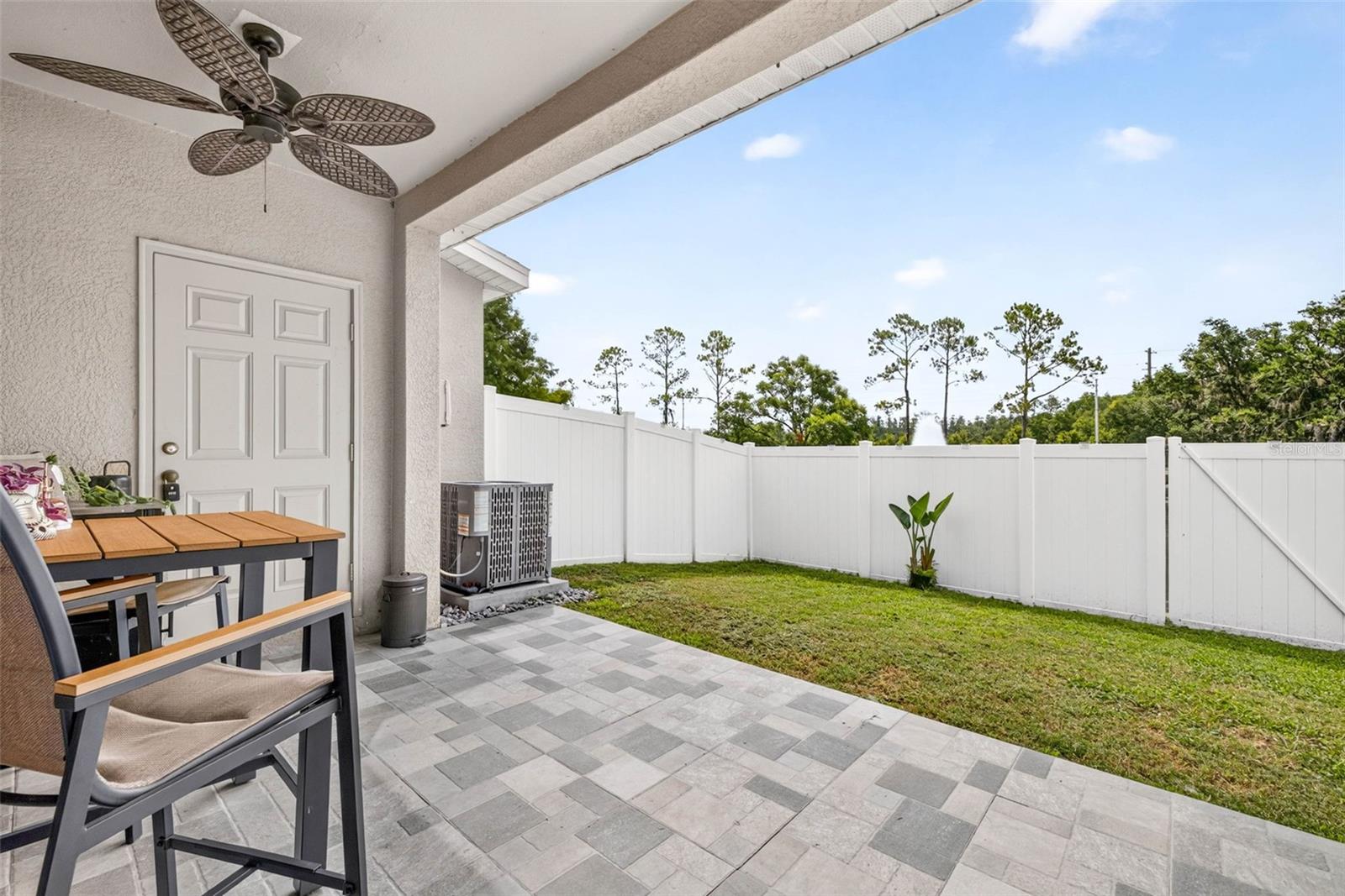 Outdoor living space with upgraded pavers and fenced yard.