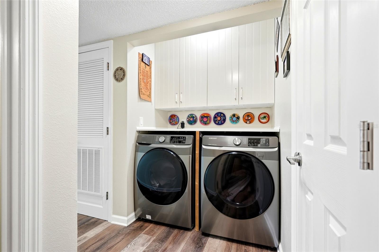 Laundry with full-size washer, dryer, and overhead storage cabinets.