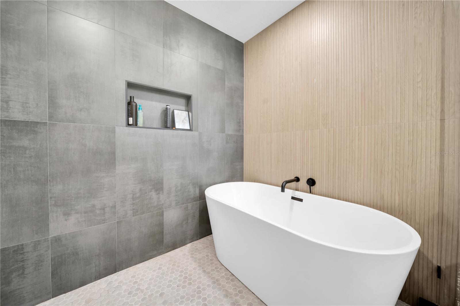 freestanding soaking tub and rain shower within a glass-enclosed wet room