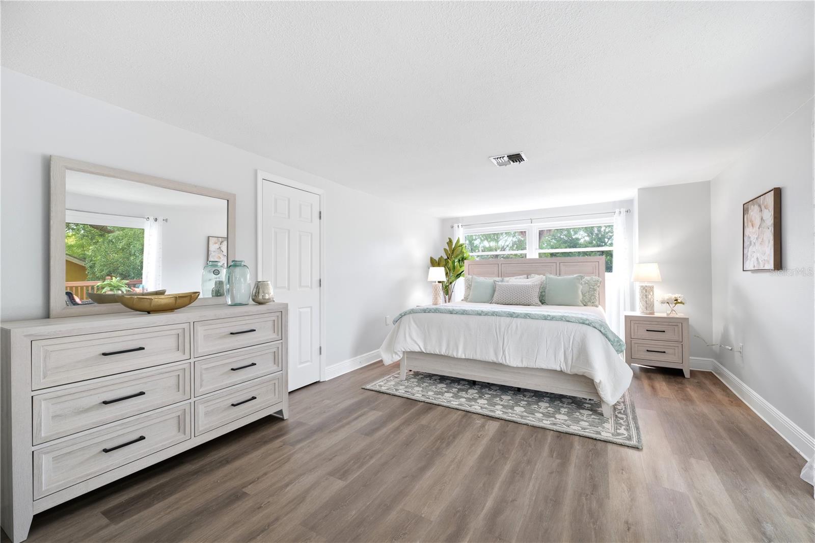 Oversized primary retreat with extra storage closet another walk in closet with custom shelving and luxury vinyl flooring , with adjoining ensuite bathroom and walk out to a private upper deck patio