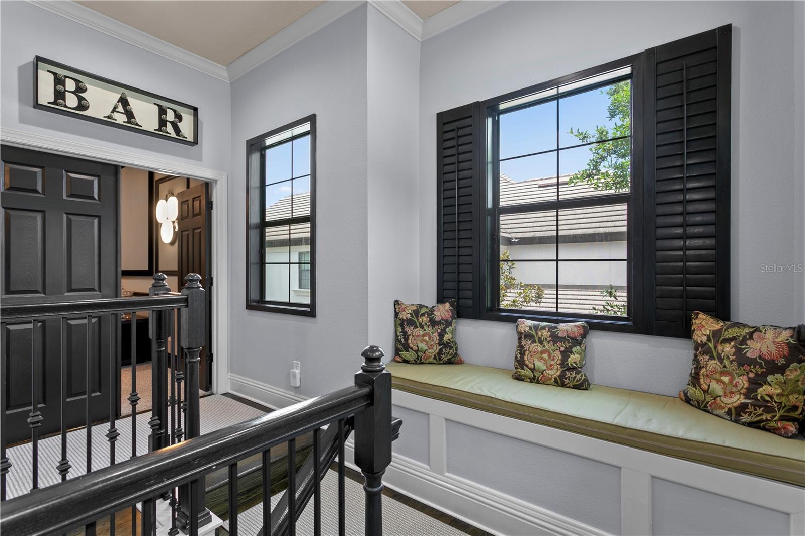 Charming landing area featuring a custom built-in window seat with elegant black plantation shutters.