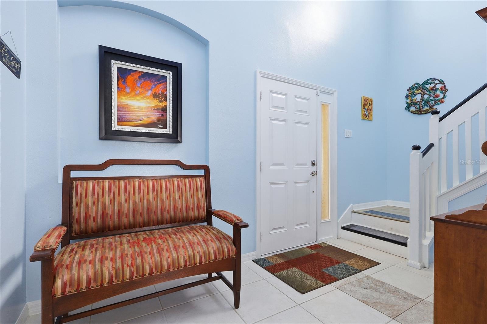 Bright arched foyer with soaring ceilings and coastal artwork