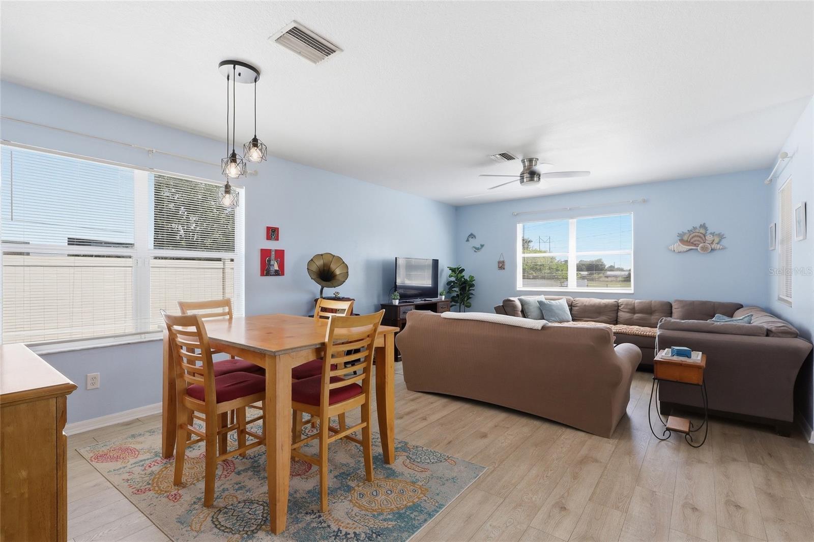 Open dining and living area with pendant lighting and vinyl plank floors
