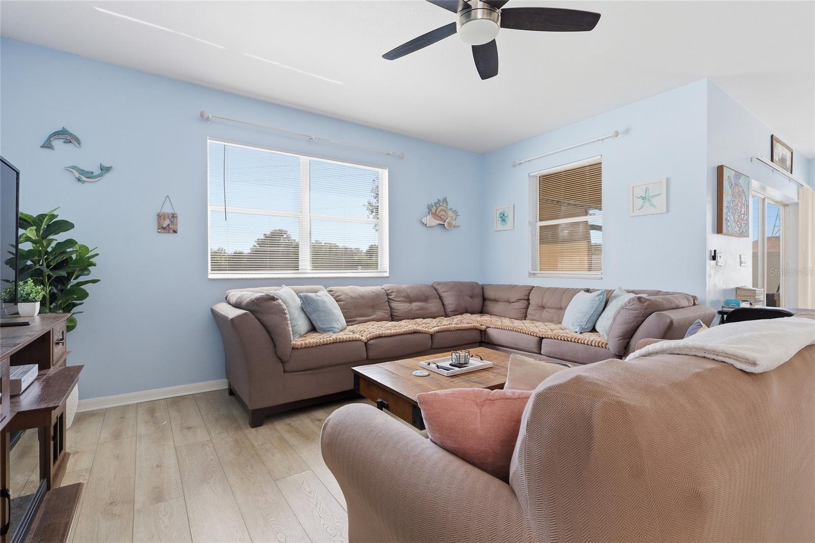 Spacious coastal living room with large sectional and ceiling fan