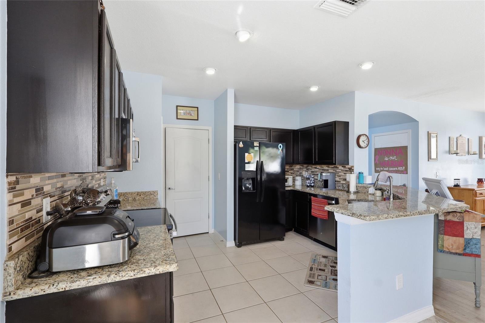 Open-concept kitchen with granite countertops and espresso cabinets