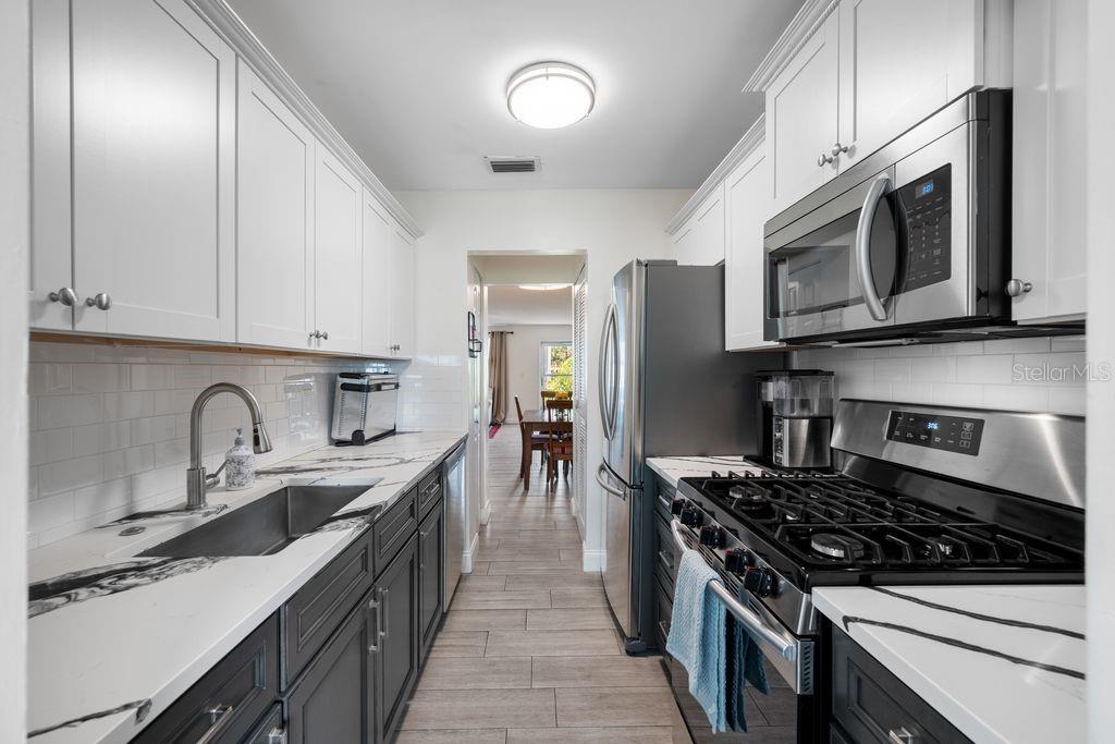 Gorgeous Galley Kitchen - Modern Two-Tone Cabinets, Quartz Countertops, Gas Range, Single Basin SinkView Into Dining Room