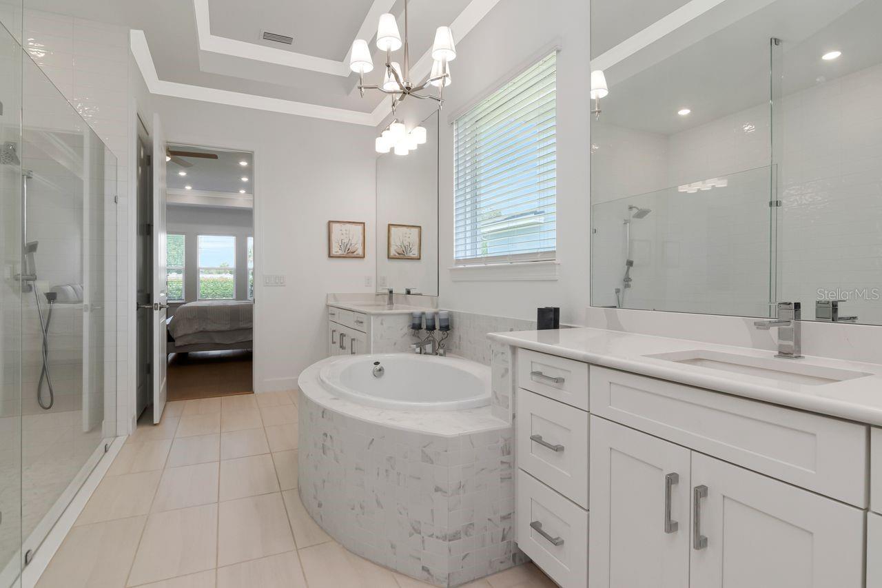 Primary En-Suite Bathroom - Quartz Countertops - Separate Dual Vanities - Glass Frame Enclosed Shower - Tray Ceiling with Crown Molding - Access Custom Walk-In Closet