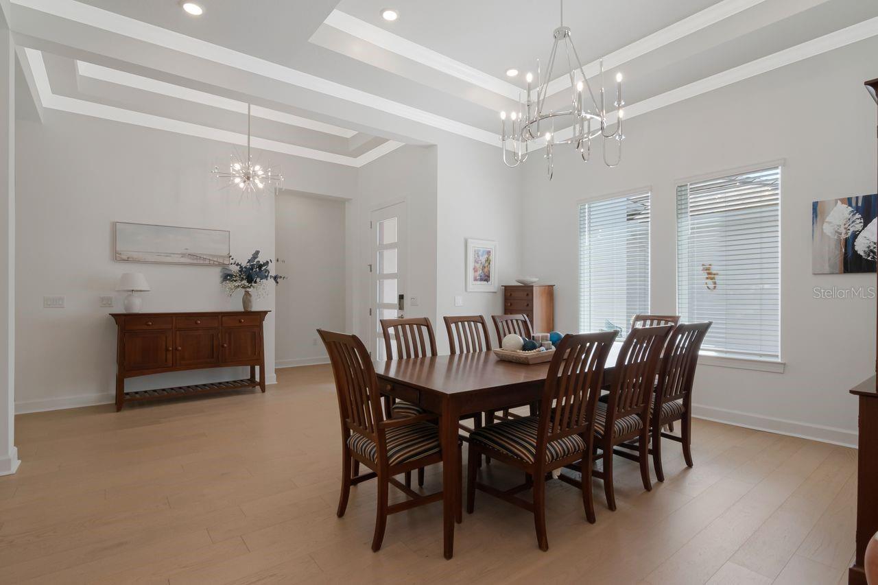 Formal Dining Room, Tray Ceilings with Crown Molding - Chandelier - Engineered Hardwood Floor - View of Entry
