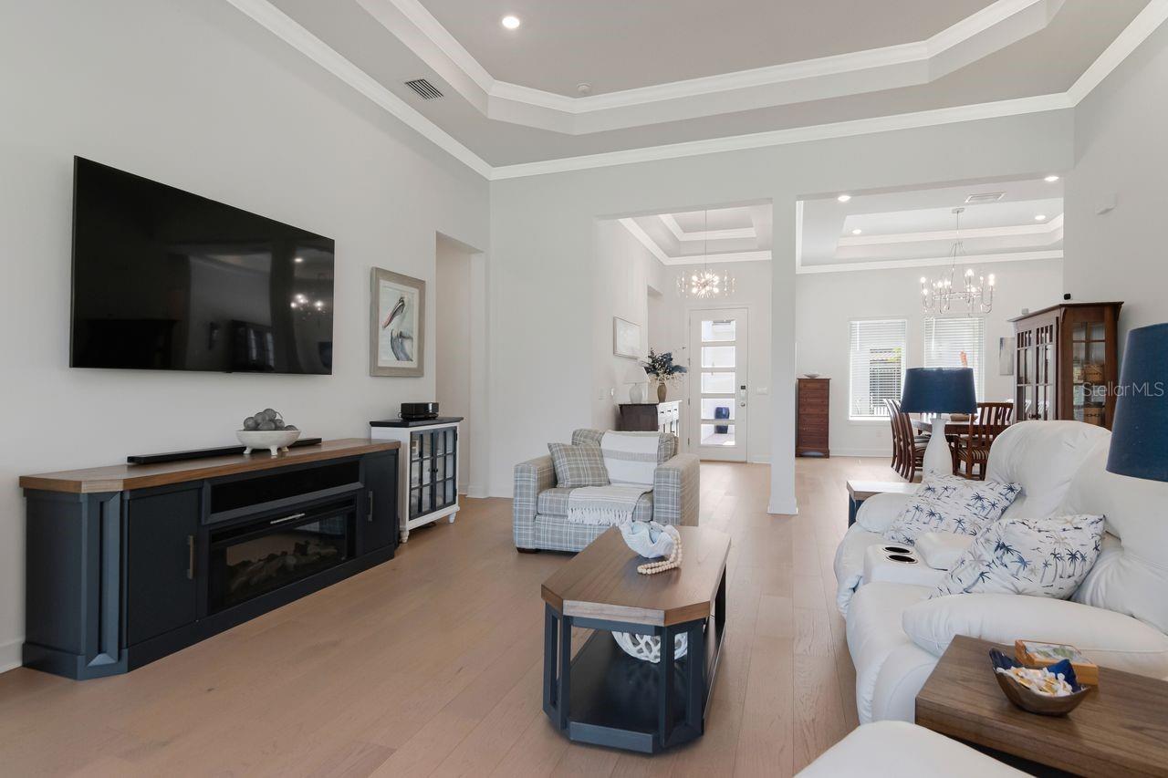 Living Room - Tray Ceiling with Crown Molding - Upgraded Ceiling Fan - Engineered Hardwood Floor - Electrical Floor Outlet - View to Dining & Entryway