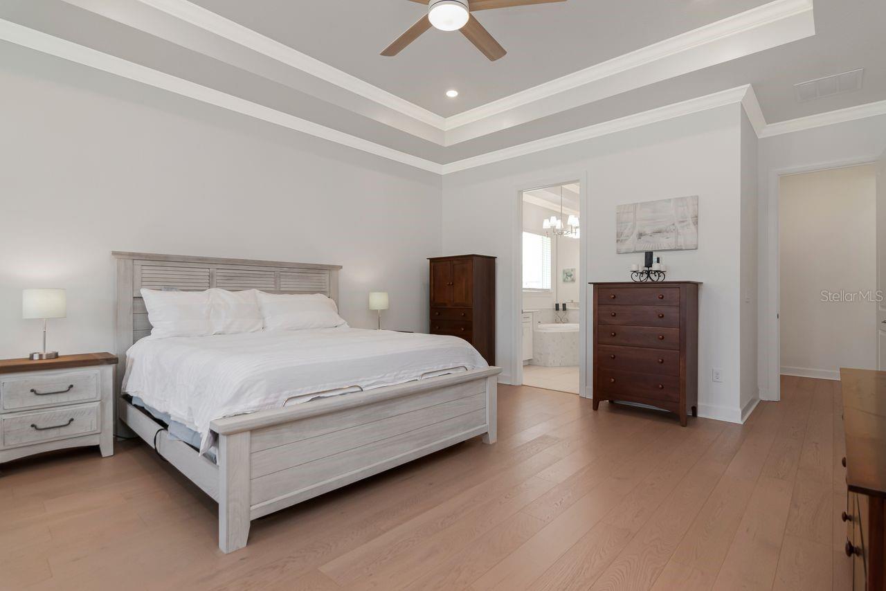 Primary Suite with En-Suite Bathroom - Extended Sitting Room Area - Tray Ceiling with Crown Molding - Engineered Hardwood Floor - Door to Access Lanai - Recessed Lighting